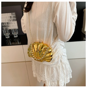 Detail of a golden shell evening bag featuring pearl edges and a metallic chain strap
