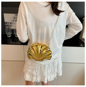 Detail of a gold seashell-shaped crossbody bag with metallic chain and bead accents
