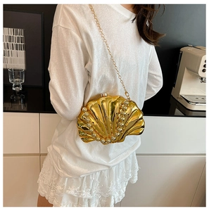 Detail of golden shell-shaped evening bag featuring pearl inlays and a fine chain strap