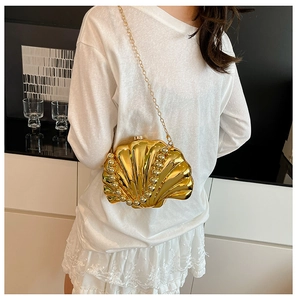 Detail of shell-shaped evening bag with gold metallic finish and pearl accents