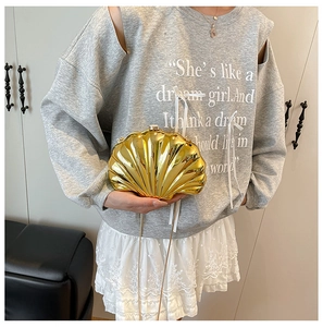 Macro view of metallic gold shell-shaped clutch bag featuring textured surface and chain strap