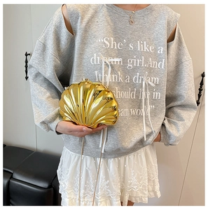 Detail of a gold shell-shaped clutch bag with metallic texture and fine chain strap