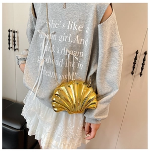 Detailed macro of golden shell-shaped mini bag with metallic texture and chain strap