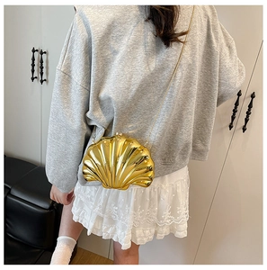 Detailed view of luxury gold shell-shaped mini bag with metallic texture and chain strap