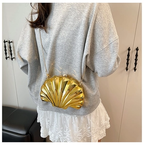 Chic gold shell-shaped crossbody mini bag with chain strap worn by a model