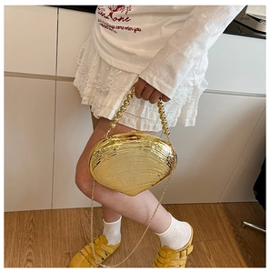 Close-up of golden shell clutch bag with beaded handle and fine chain strap detail