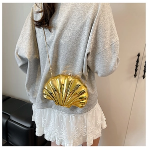 Detailed close-up of a mini gold shell-shaped crossbody bag with a sleek metallic finish