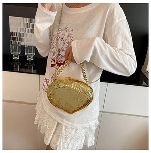 Detailed view of a gold shell-shaped clutch bag with bead handle and chain strap