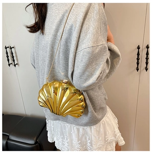 Chic gold shell-shaped crossbody bag with metallic texture and chain strap on model