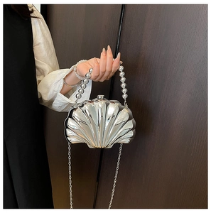 Detail of silver shell-shaped mini bag with pearl handle and metallic chain strap