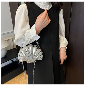 Detailed view of silver shell-shaped mini bag with pearl handle and chain strap