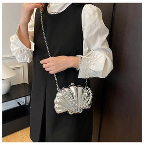Silver shell-shaped crossbody bag featuring pearl handle and glossy metallic finish