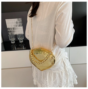Detailed view of a gold shell-shaped clutch with a pearl handle and chain strap