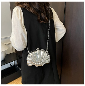 Detail of silver shell-shaped chain bag with pearl trim on a model's shoulder