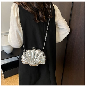 Silver shell-shaped clutch evening bag with pearl trim and delicate chain strap shown on model