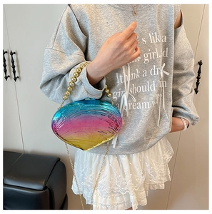 Detail of shell-shaped gradient acrylic clutch bag with golden bead handle and chain