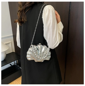 Close-up of a silver shell-shaped mini bag featuring pearl handle and metal chain