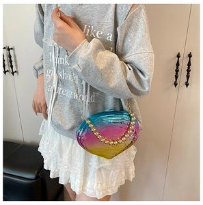 Detail view of a shell-shaped acrylic clutch bag with a rainbow gradient and gold chain