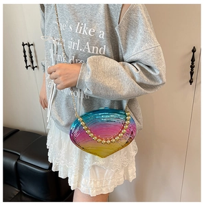 Detail of shell-shaped gradient acrylic evening bag with gold bead handle and metal chain
