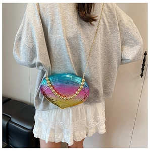 Close-up of iridescent shell texture acrylic evening bag with gold chain and bead handle