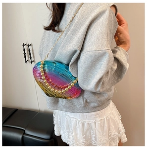 Close-up of holographic shell-shaped bag with gold bead handle and metallic chain strap