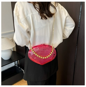 Detailed view of pink acrylic shell bag featuring golden bead handle and fine chain strap