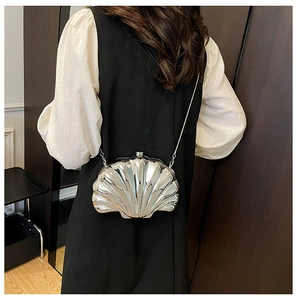 Detail view of silver shell-shaped mini bag with metallic chain on a female model