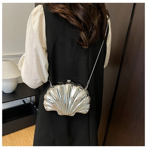 Detail showing shell-shaped silver mini bag with metallic texture and chain strap