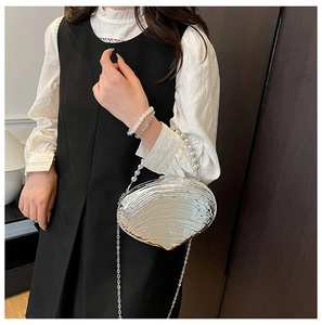Detail of silver shell evening bag with beaded handle and metal chain strap on model