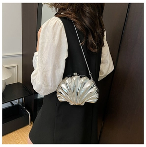 Silver shell-shaped crossbody bag with metallic finish and snake chain on model