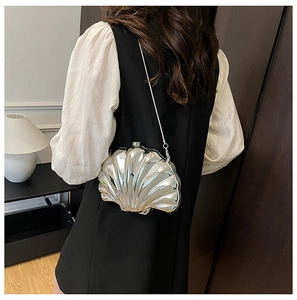 Silver metallic shell-shaped crossbody bag with slim chain strap shown on a model