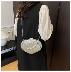 Detail of silver shell-shaped evening bag with pearl handle and metal chain strap