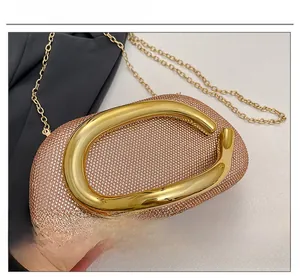 Close-up of sparkling rhinestone clutch bag with a gold C-shaped metal handle and chain