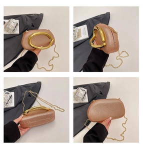 Detail of rose gold rhinestone evening bag featuring a large metallic oval handle and chain