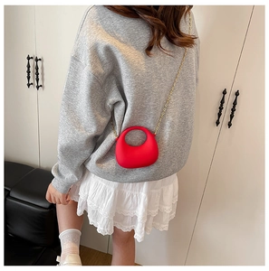 Red crescent silicone mini bag with golden chain strap shown on a shoulder