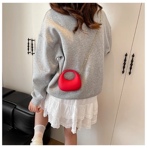 Red half-moon acrylic handbag with gold chain strap shown in a daily lifestyle setting