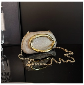 Macro shot of luxury gold rhinestone evening clutch bag with glossy oval metal handle