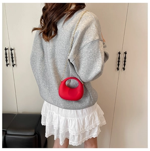 Chic red acrylic mini handbag with gold chain strap shown on model for size reference