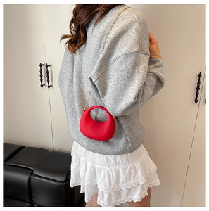 Red mini circular acrylic handbag with gold chain strap shown on crossbody model