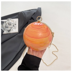 Detail of spherical marble acrylic clutch bag with gold ring handle and chain strap