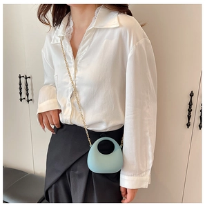 Close-up of light blue mini bag with circular handle and detachable gold chain strap