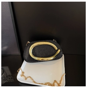 Close-up of black glitter evening bag with large gold metal handle and chain strap