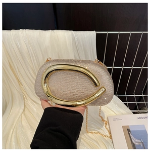 Close-up of champagne gold evening clutch with rhinestones and curved metal handle
