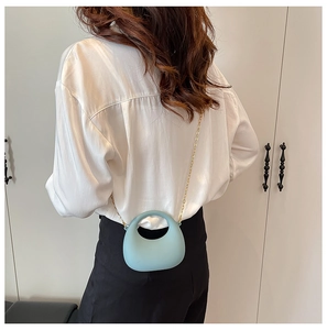 Back view of model wearing a mini light blue acrylic handbag with gold chain strap