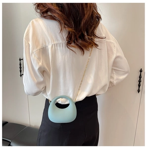 Detail of light blue mini acrylic handbag with round handle and metal chain strap