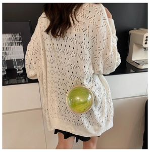 Chic spherical crossbody bag in green marble acrylic held by model in casual setting