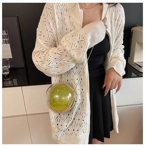 Detail of creative sphere handbag with transparent shell and green lining on gold chain