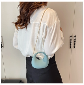Detailed side view of a light blue acrylic mini bag with gold chain and round handle