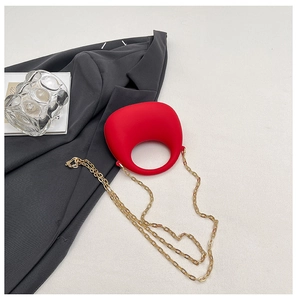 Detail of red geometric acrylic handbag with round handle and gold chain strap