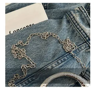 Polished silver metal chain strap and hammered ring detail on blue denim fabric